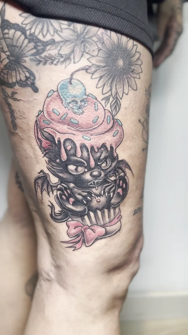 Cupcake con rostro y lazo en tonos rosa y negro en el muslo