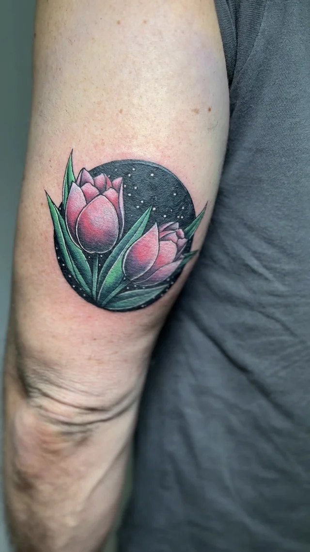 Tulipanes rosas con hojas verdes en composición circular en el brazo