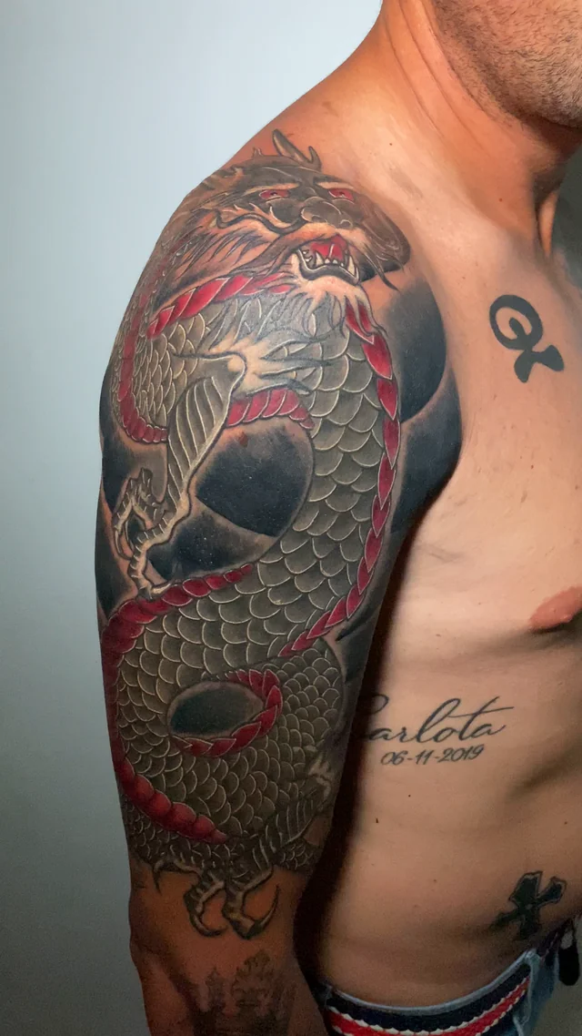 Dragón japonés rojo y verde sobre hombro y brazo